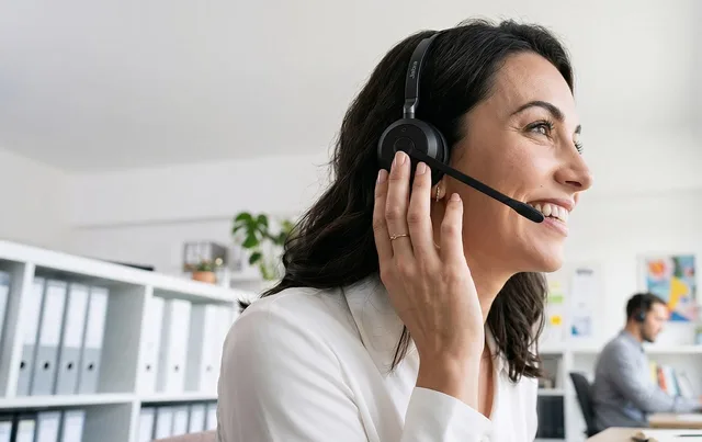 office, headset, smiling woman, headset microphone, workplace, interaction, call center, conversation, professional, communication, customer service, woman, smile, white shirt, satisfaction, working, happy worker, administrative, telephone call. Support reporting technology